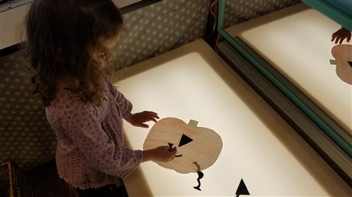 Student decorating a paper pumpkin at the light table. Student decorating a paper pumpkin at the light table.