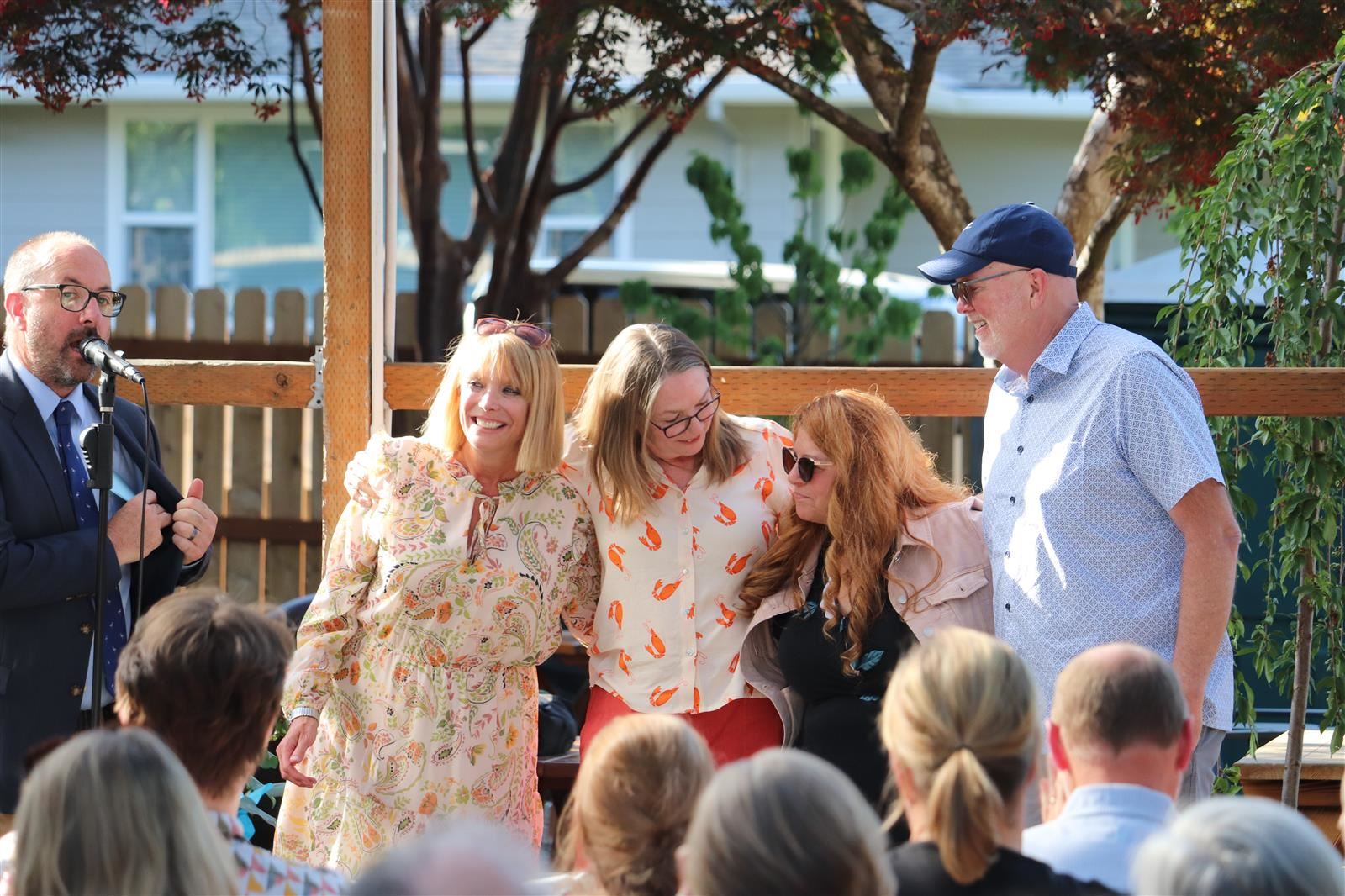 Four teachers stand arm in arm as they're celebrated by peers. 